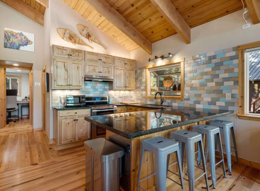 Experience rustic charm in this mountain kitchen featuring light wood cabinetry and a spacious granite island with bar seating.