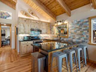 Experience rustic charm in this mountain kitchen featuring light wood cabinetry and a spacious granite island with bar seating.
