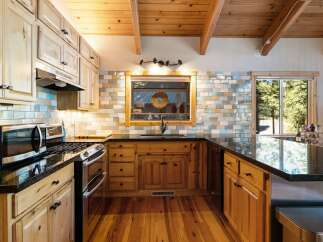 This charming kitchen boasts beautiful natural wood cabinetry and a rustic wooden ceiling with exposed beams.