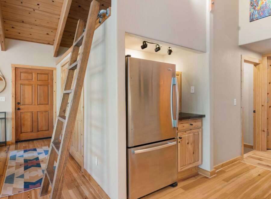 Discover rustic charm in this inviting space featuring a unique wooden ladder leading to a loft area, perfect for maximizing space.