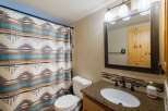 This bathroom features a stylish shower curtain with a Native American-inspired pattern, complementing the granite countertop and wooden vanity.
