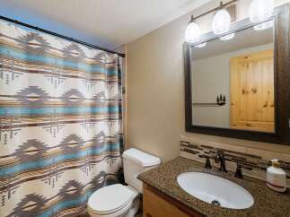 This bathroom features a stylish shower curtain with a Native American-inspired pattern, complementing the granite countertop and wooden vanity.