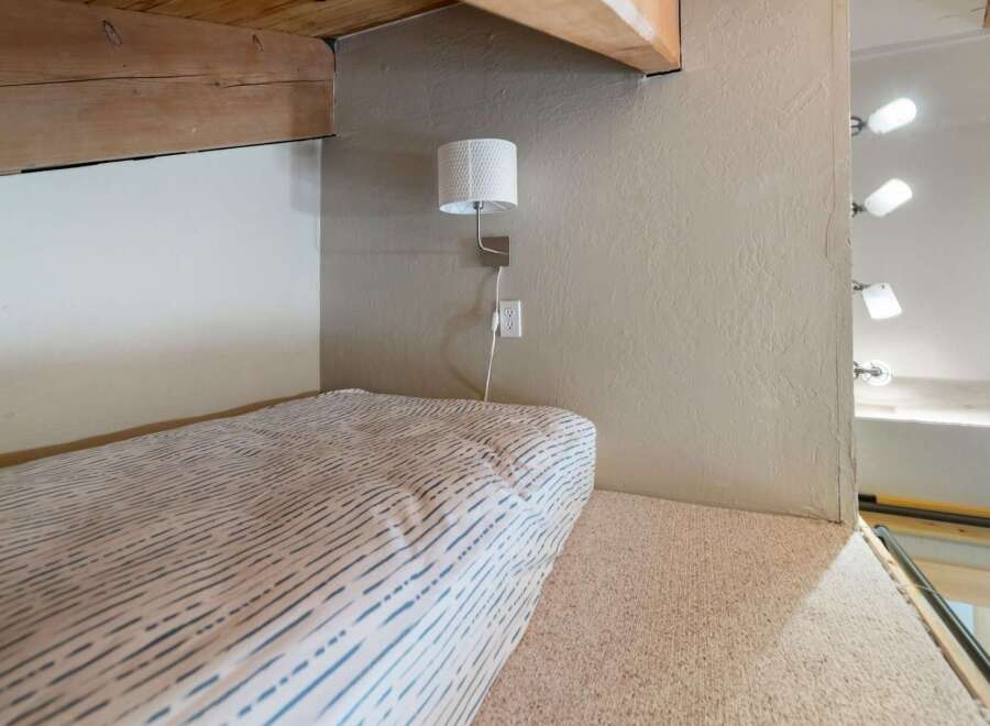 This cozy loft space features a comfortable bed with a striped duvet, perfect for a relaxing retreat.