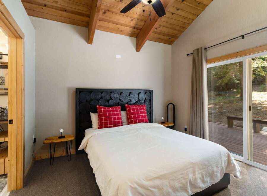 Experience rustic charm in this inviting bedroom, featuring a unique log-style headboard and cozy plaid pillows.