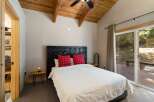 Experience rustic charm in this inviting bedroom, featuring a unique log-style headboard and cozy plaid pillows.