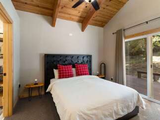 Experience rustic charm in this inviting bedroom, featuring a unique log-style headboard and cozy plaid pillows.