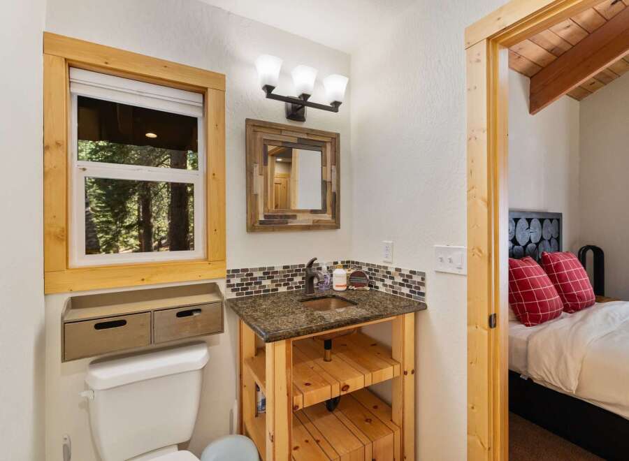 This charming bathroom features a rustic wooden vanity with a granite countertop and a copper sink, complemented by a mosaic tile backsplash.