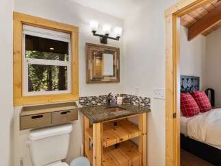 This charming bathroom features a rustic wooden vanity with a granite countertop and a copper sink, complemented by a mosaic tile backsplash.