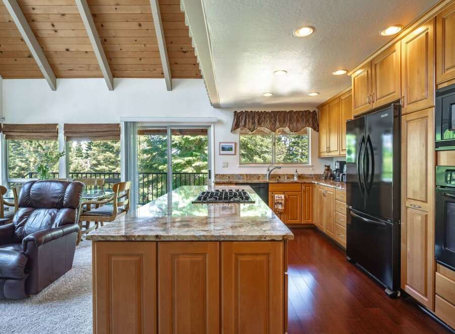 Experience the best of indoor-outdoor living in this stunning kitchen and dining area, featuring a spacious island with a built-in gas range and granite countertops.