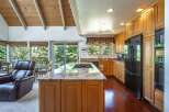 Experience the best of indoor-outdoor living in this stunning kitchen and dining area, featuring a spacious island with a built-in gas range and granite countertops.
