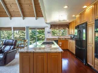 Experience the best of indoor-outdoor living in this stunning kitchen and dining area, featuring a spacious island with a built-in gas range and granite countertops.