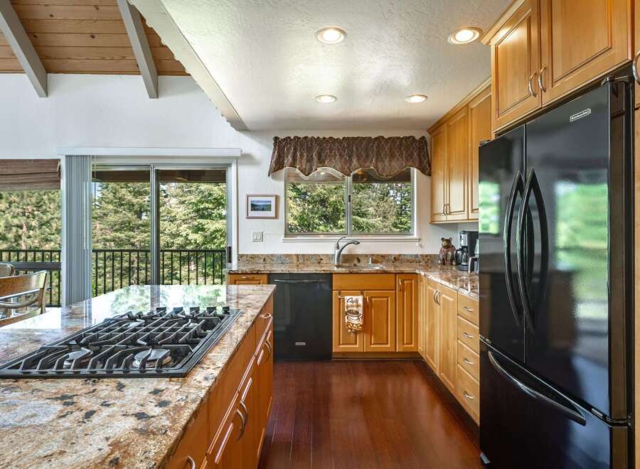 This spacious kitchen boasts a large granite island with a built-in gas stovetop, perfect for culinary enthusiasts.
