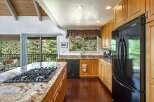 This spacious kitchen boasts a large granite island with a built-in gas stovetop, perfect for culinary enthusiasts.