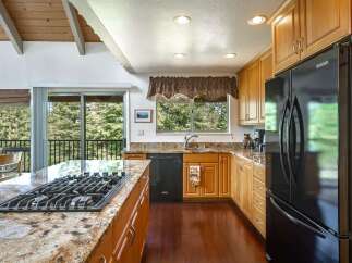 This spacious kitchen boasts a large granite island with a built-in gas stovetop, perfect for culinary enthusiasts.
