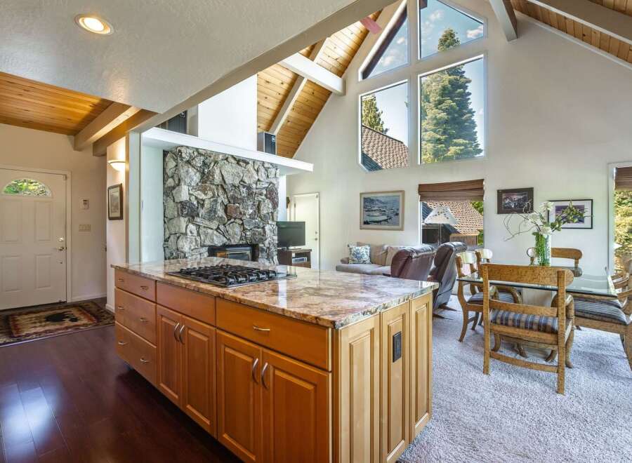 Experience breathtaking mountain views from this stunning open-concept living space, featuring a grand stone fireplace and vaulted wood-beamed ceilings.