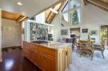 Experience breathtaking mountain views from this stunning open-concept living space, featuring a grand stone fireplace and vaulted wood-beamed ceilings.