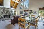 Experience breathtaking mountain views from this stunning living and dining area, featuring a grand stone fireplace and vaulted wood-beamed ceilings.