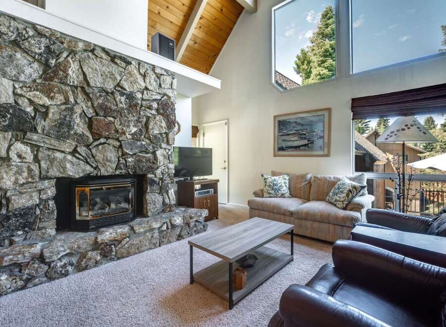 Experience cozy living in this inviting living room, featuring a magnificent floor-to-ceiling stone fireplace that serves as the heart of the space.