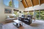 Experience breathtaking views from this stunning living room, featuring a grand vaulted ceiling with exposed wood beams and expansive windows that flood the space with natural light.