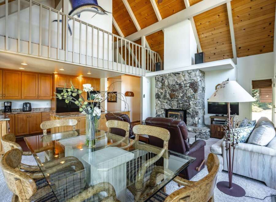 Experience spacious living in this open-concept home featuring a stunning stone fireplace and a vaulted wood-beamed ceiling.