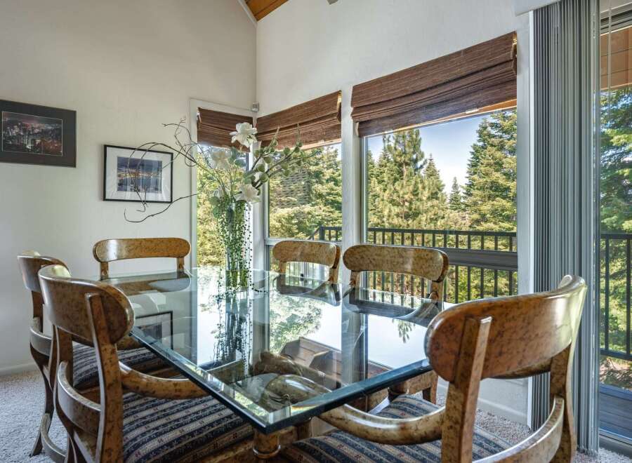 Dine with a view in this elegant dining room featuring a glass-top table and unique wooden chairs.