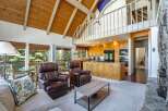 Experience rustic charm and modern comfort in this spacious living area, featuring a vaulted wood-beamed ceiling and a cozy stone fireplace.