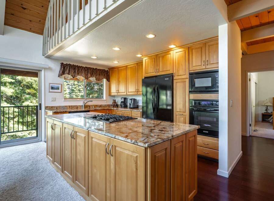 This spacious kitchen boasts a large granite island with a built-in gas stovetop, perfect for culinary enthusiasts.
