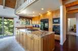 This spacious kitchen boasts a large granite island with a built-in gas stovetop, perfect for culinary enthusiasts.