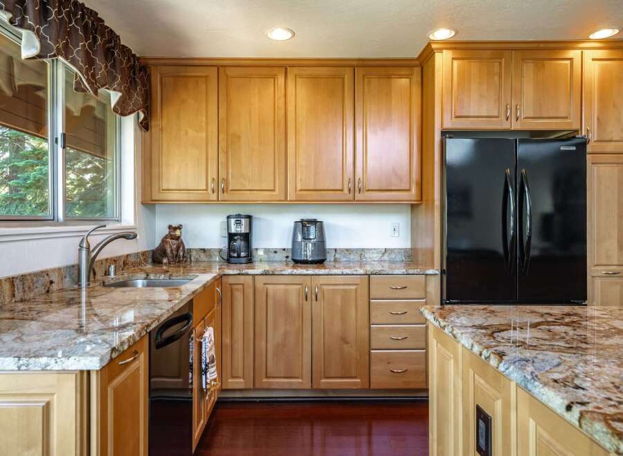 This spacious kitchen boasts beautiful light wood cabinetry and stunning granite countertops, offering a warm and inviting atmosphere.