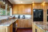 This spacious kitchen boasts beautiful light wood cabinetry and stunning granite countertops, offering a warm and inviting atmosphere.