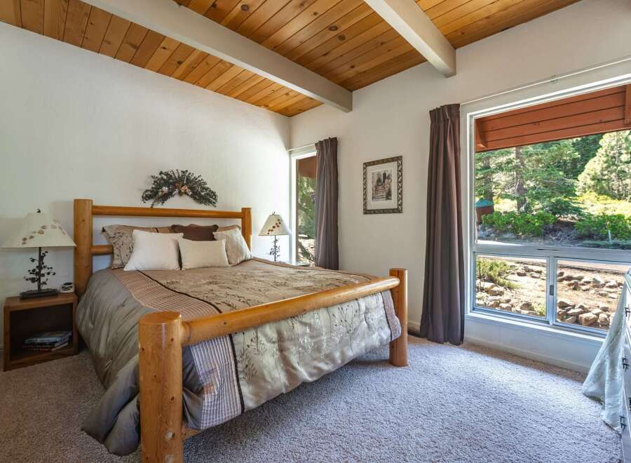 Experience rustic charm in this inviting bedroom featuring a sturdy log bed and a vaulted wood-beamed ceiling.