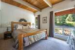 Experience rustic charm in this inviting bedroom featuring a sturdy log bed and a vaulted wood-beamed ceiling.
