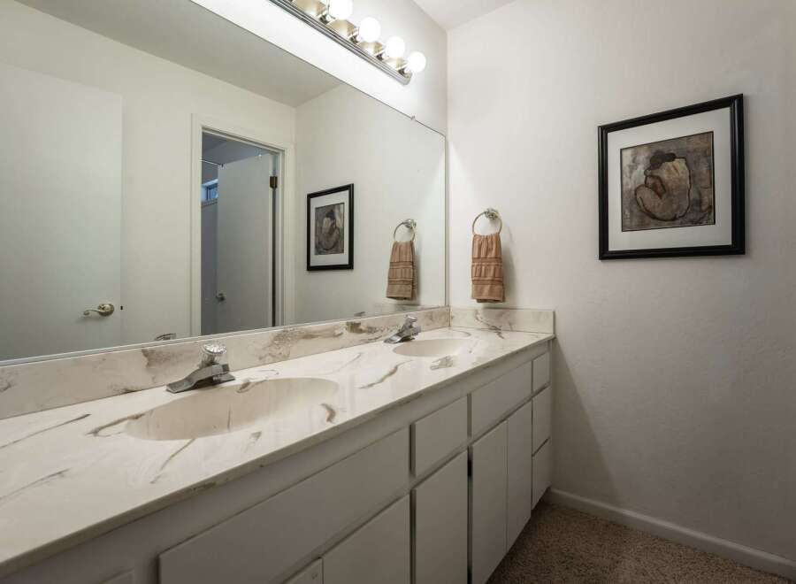 This bathroom features a spacious double vanity with a marble countertop and two undermount sinks, perfect for busy mornings.