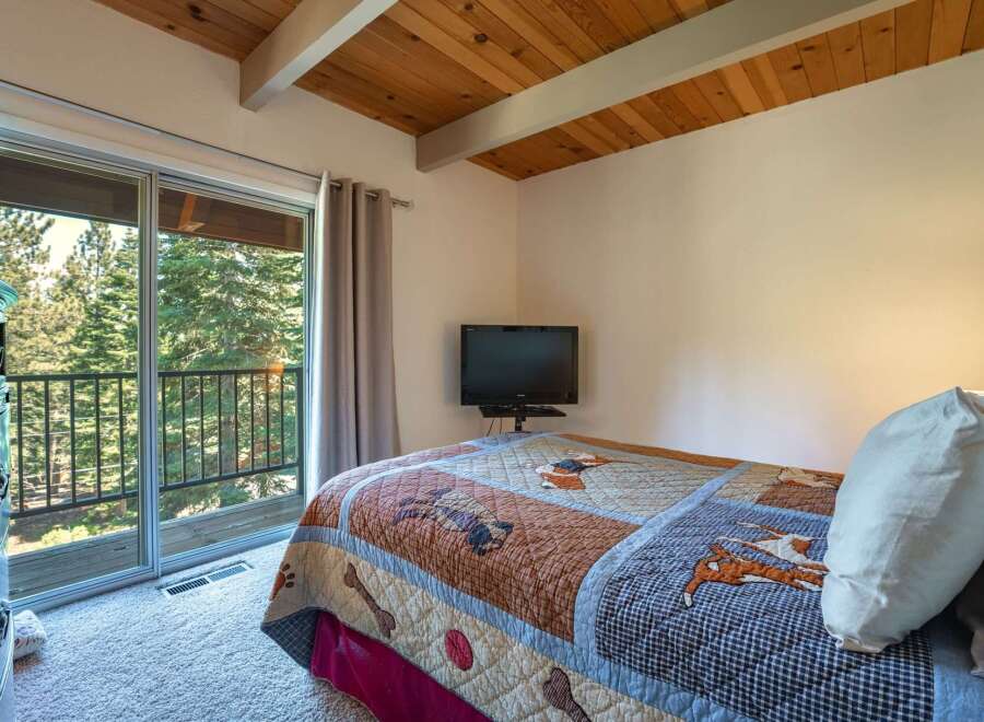 Experience mountain living with this charming bedroom featuring a cozy queen-size bed adorned with a playful dog-themed quilt.