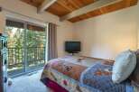 Experience mountain living with this charming bedroom featuring a cozy queen-size bed adorned with a playful dog-themed quilt.