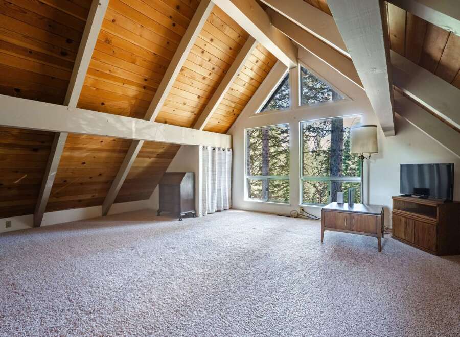 Experience the charm of this attic space, featuring a vaulted wood-paneled ceiling with exposed beams that create a warm, rustic ambiance.