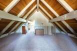 Discover this charming attic space featuring a vaulted wood-paneled ceiling with exposed beams, creating a warm and inviting atmosphere.