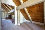 Discover a charming attic space with a unique A-frame design, featuring exposed wooden beams and paneled walls that add rustic warmth.