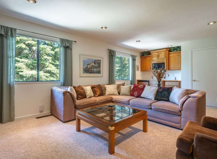 This spacious living area features a large sectional sofa perfect for gatherings, complemented by a stylish wooden coffee table with a glass top.