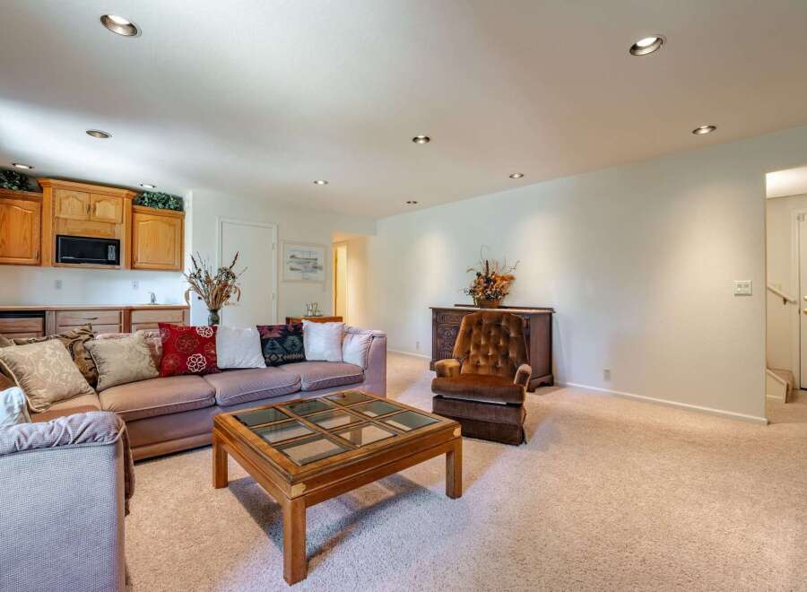This spacious living area features a comfortable sectional sofa and a plush armchair, perfect for relaxation.