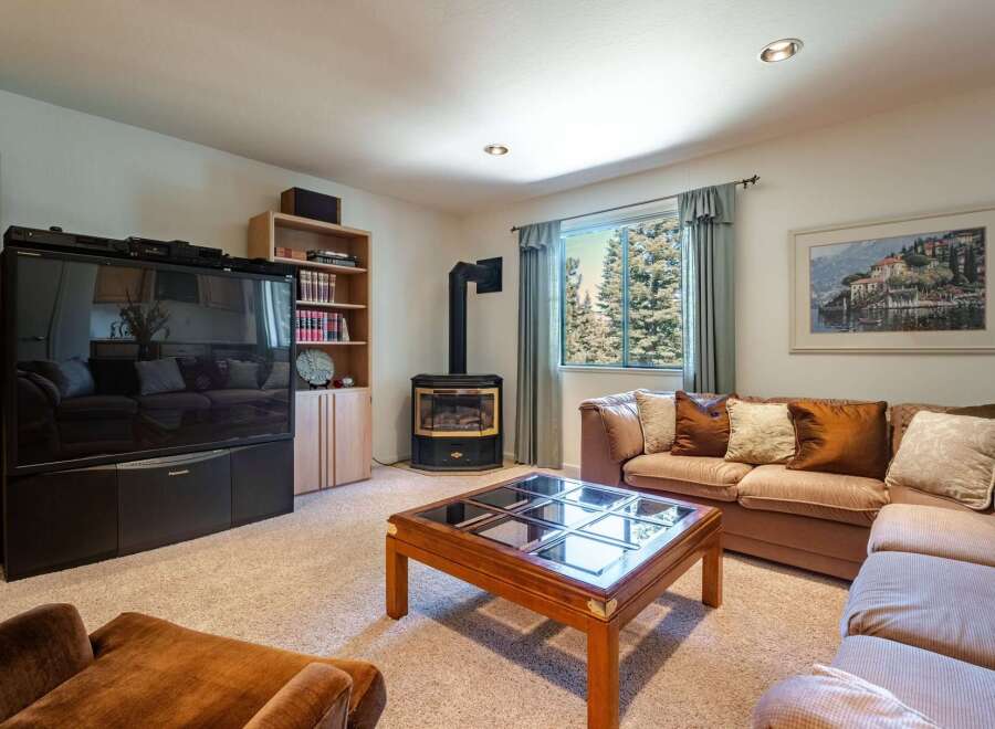 Cozy living room featuring a large flat-screen TV, a wood-burning stove, and comfortable seating arrangements.