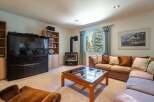 Cozy living room featuring a large flat-screen TV, a wood-burning stove, and comfortable seating arrangements.