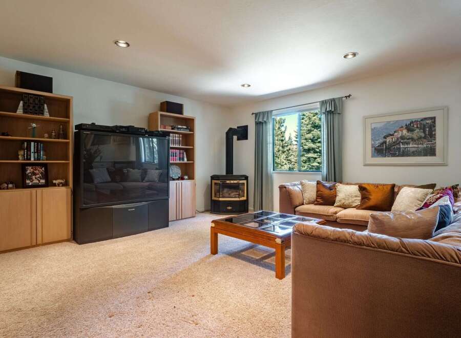 Cozy living room featuring a large sectional sofa adorned with decorative pillows, a glass-top coffee table, and a modern wood-burning stove.