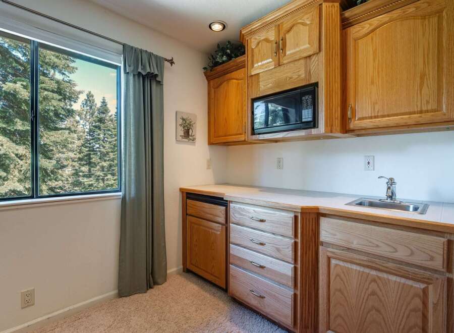 This charming kitchenette area features a built-in microwave, a convenient sink, and ample cabinet and drawer storage, perfect for a guest suite or in-law unit.