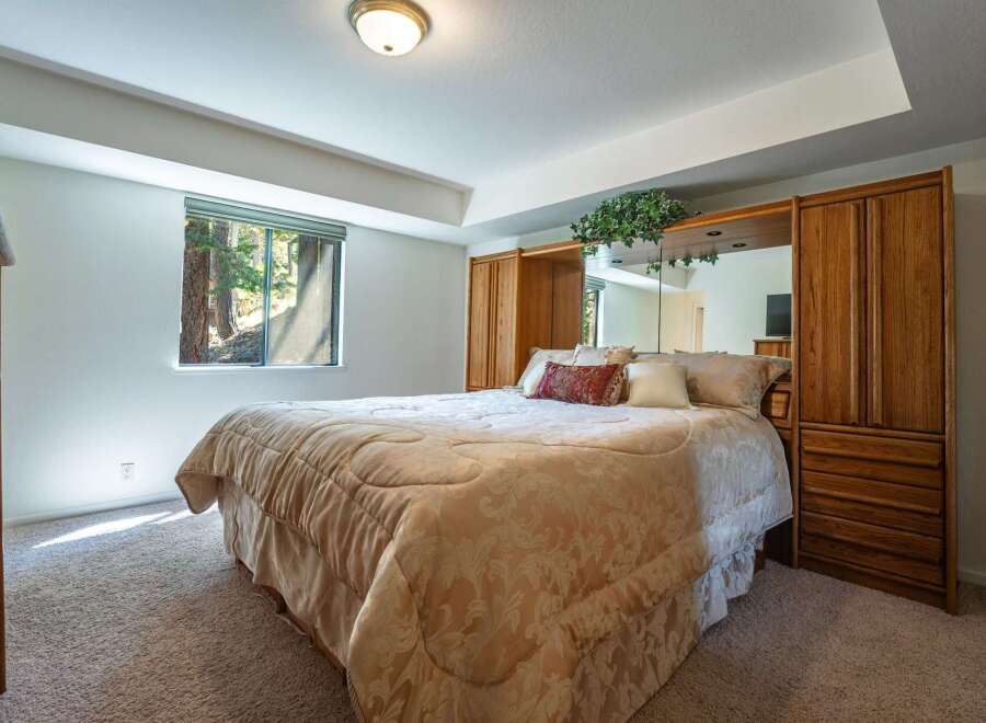Experience serene living in this charming bedroom, featuring a plush queen-size bed adorned with a damask comforter and decorative pillows.