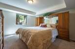 Experience serene living in this charming bedroom, featuring a plush queen-size bed adorned with a damask comforter and decorative pillows.