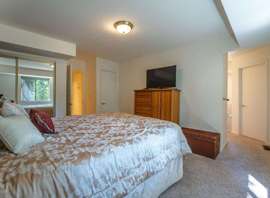 This inviting bedroom features a spacious bed with a luxurious patterned comforter, complemented by a wooden dresser and a flat-screen TV.