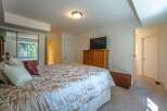 This inviting bedroom features a spacious bed with a luxurious patterned comforter, complemented by a wooden dresser and a flat-screen TV.