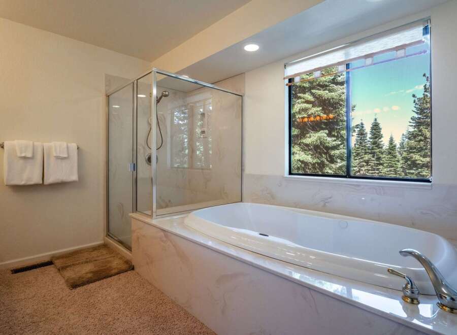 Indulge in relaxation in this luxurious bathroom featuring a spacious soaking tub with a stunning view of evergreen trees.