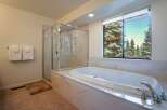 Indulge in relaxation in this luxurious bathroom featuring a spacious soaking tub with a stunning view of evergreen trees.